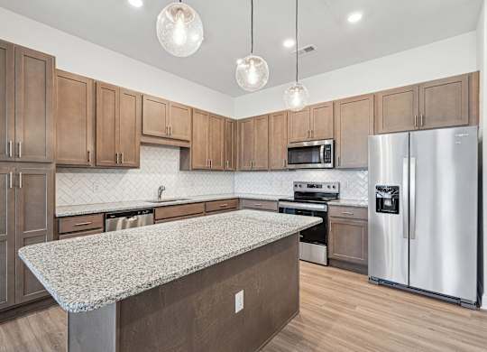 A kitchen with wooden cabinets and a granite countertop.at The Parker Leland, North Carolina