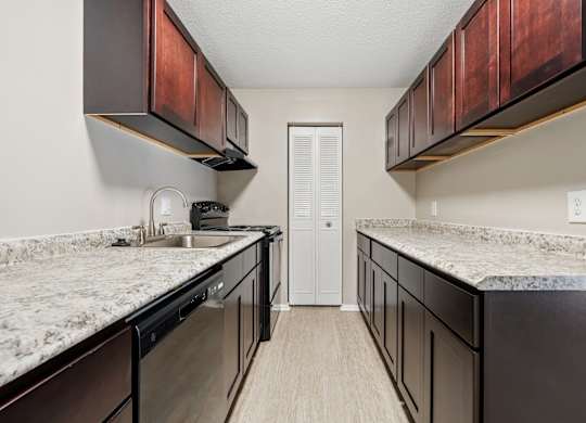 A kitchen with dark brown cabinets and granite countertops.