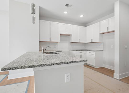A kitchen with white cabinets and a granite countertop.