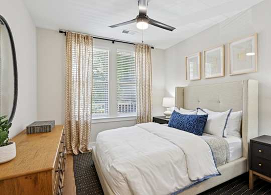 A bedroom with a large bed, a ceiling fan, and a window with curtains at Union Eleven Apartments, Atlanta