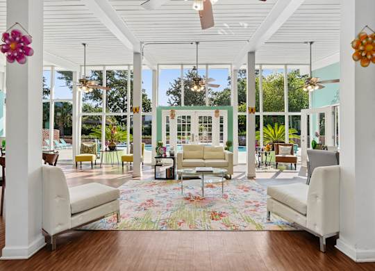 A white room with a floral rug and two white chairs.