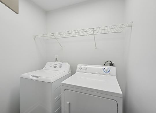 Two white front loading washing machines in a laundry room.