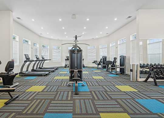 A gym with a variety of equipment including treadmills, weights, and exercise machines at The Parker Leland, Leland, NC 28451