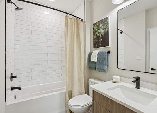 A white bathroom with a toilet, sink, and shower at Union Eleven Apartments, Atlanta, GA