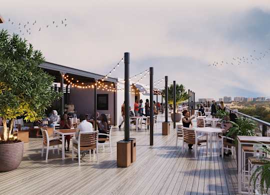 A group of people are sitting at tables on a wooden deck.