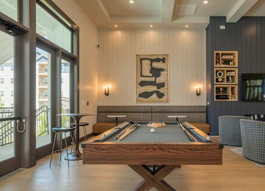 A pool table is in the middle of a room with a fireplace and a TV at The Ashton at East Park Apartments, Georgia, 30144