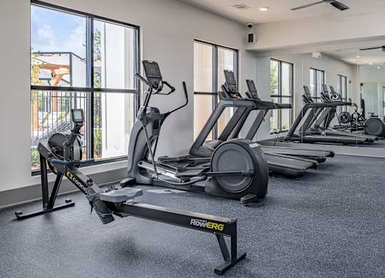 A gym with a variety of equipment including treadmills and elliptical machines at The Collective Upper Westside Apartments, Atlanta
