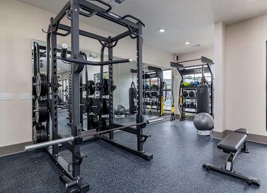 A gym with a variety of equipment including a squat rack, bench, and weights at The Collective Upper Westside Apartments, Atlanta, 30318