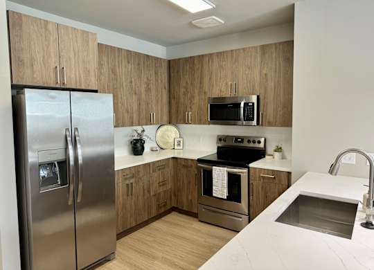 A kitchen with a stainless steel refrigerator, microwave, oven, and sink at The Collective Upper Westside Apartments, Atlanta, 30318
