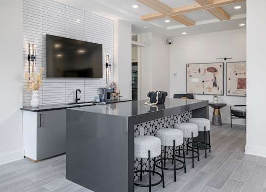 A modern kitchen with a bar area and stools at The Collective Upper Westside Apartments, Georgia