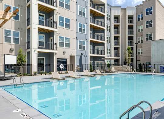 A swimming pool in front of a multi-story apartment building at The Collective Upper Westside Apartments, Atlanta, GA, 30318