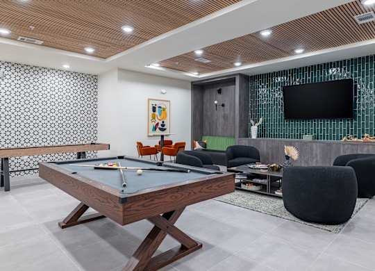 A billiard table is in the middle of a room with a television and a pool table at The Collective Upper Westside Apartments, Atlanta, GA