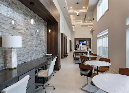 A modern dining area with a stone wall and a television at The Waverly at Winter Haven Apartments, Winter Haven, Florida