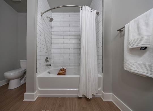 A white bathroom with a toilet, a bathtub, and a towel rack at The Waverly at Winter Haven Apartments, Florida, 33884