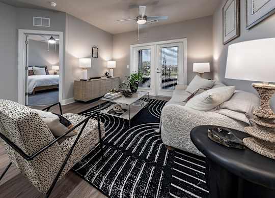 A well-lit bedroom with a large bed, a chair, and a coffee table at The Waverly at Winter Haven Apartments, Florida