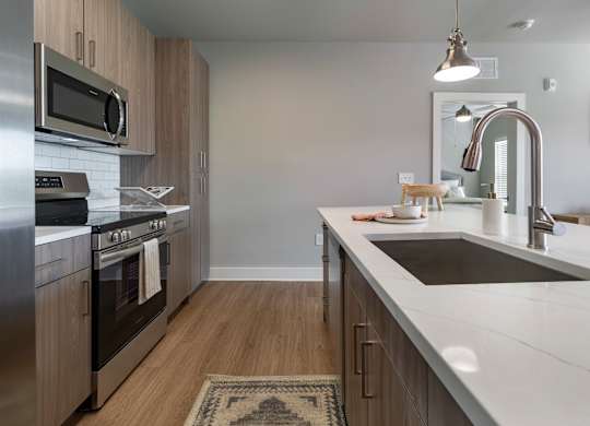 A modern kitchen with stainless steel appliances and wooden cabinets at The Waverly at Winter Haven Apartments, Florida, 33884