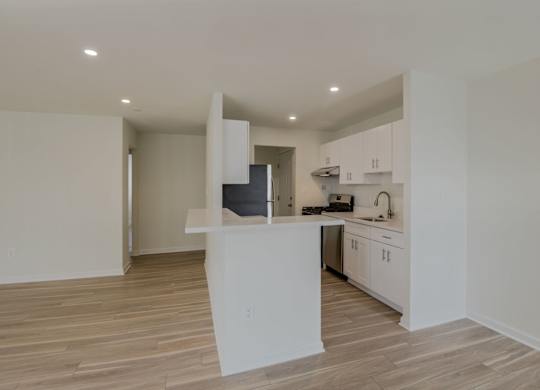 A kitchen with white cabinets and a wooden floor.