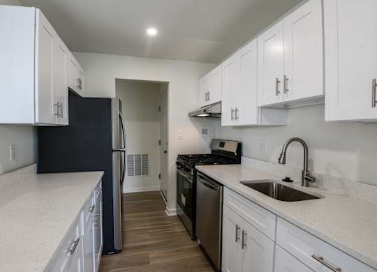 A kitchen with white cabinets and a black refrigerator.