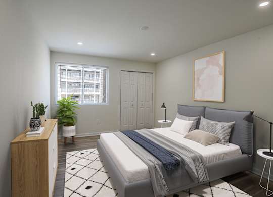 A bedroom with a bed, nightstand, and a plant.