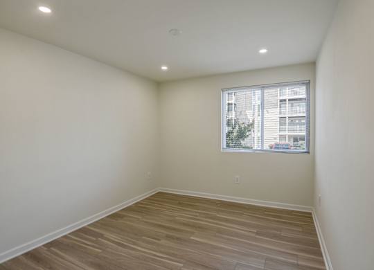 Empty room with wooden flooring and a window.