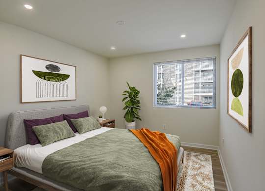 A bedroom with a bed, a potted plant, and two framed pictures on the wall.