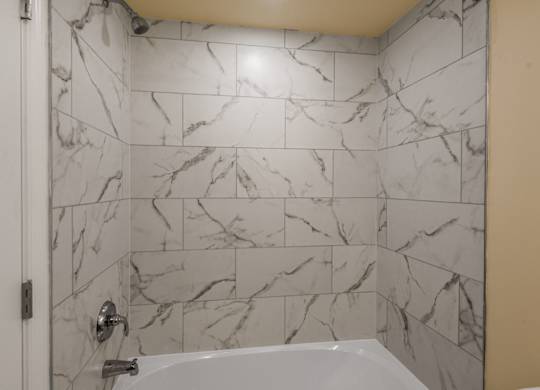 A white bathroom with a marble tile wall.