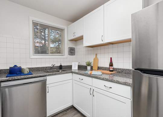 A kitchen with white cabinets and a granite counter top.