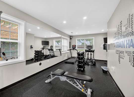 A gym room with a variety of equipment including weights and a bench.