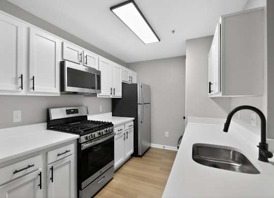 A kitchen with white cabinets and appliances.