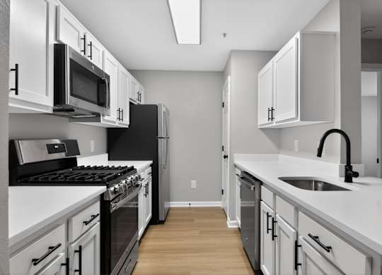 A modern kitchen with white cabinets and black appliances.