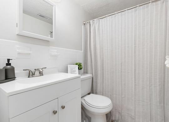 A white bathroom with a toilet, sink, and shower curtain.