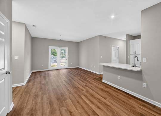 A spacious room with wooden flooring and white walls.