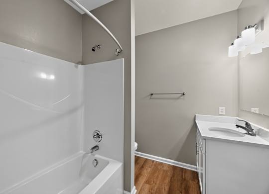 A white bathroom with a tub, sink and mirror.