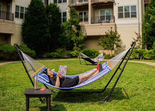 A person is lying in a hammock and reading a book.