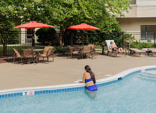 A woman in a blue bikini is sitting on the edge of a pool.