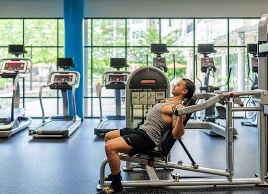 A man is working out on a leg press machine in a gym.