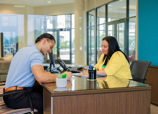 A man and a woman are sitting at a desk in an office.