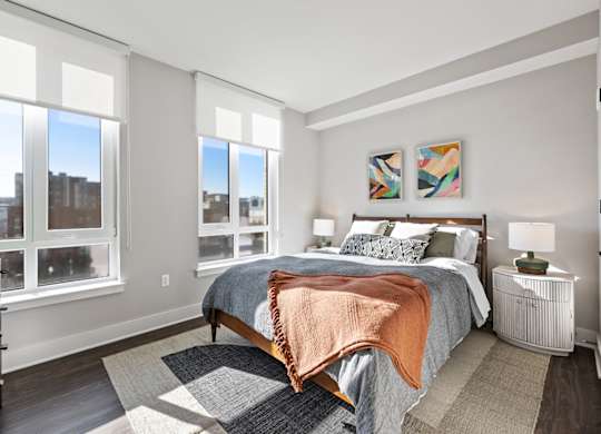 A bedroom with a large bed and a view of the city through the windows.