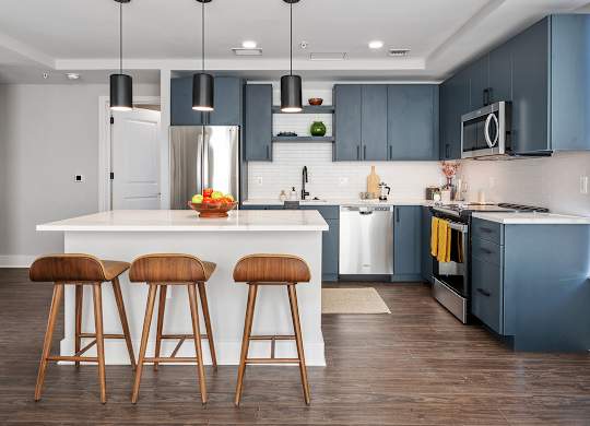 A kitchen with a white island and brown bar stools.