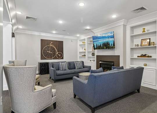 A living room with a grey couch and a painting on the wall.