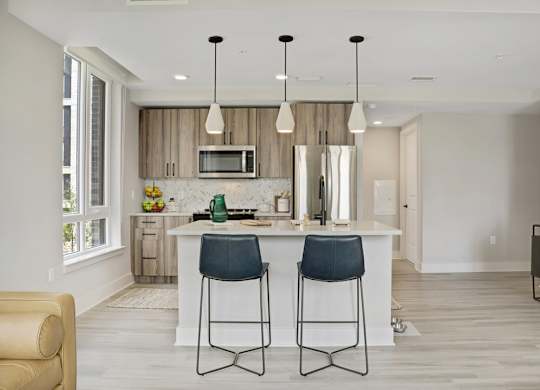 A modern kitchen with a white island and two bar stools.