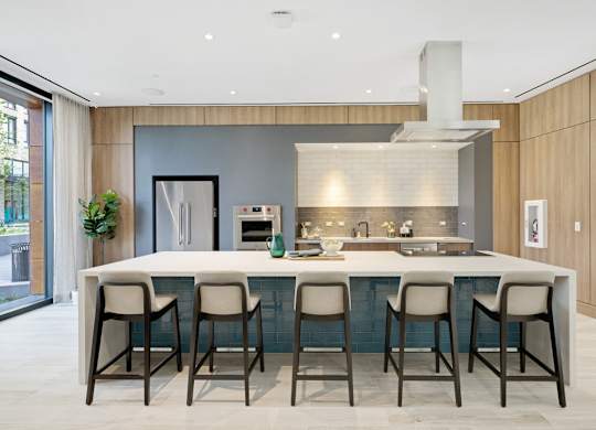 A modern kitchen with a bar area and chairs.