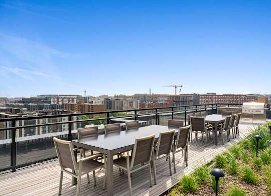 A table and chairs set up on a balcony with a view of the city.