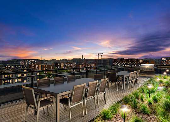 A table set for six dining on a rooftop with a cityscape in the background.