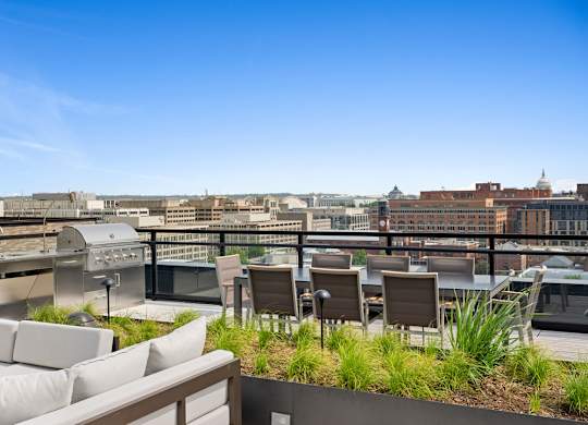 A rooftop patio with chairs and a table overlooking a cityscape.