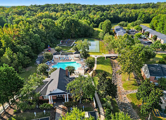 A large swimming pool surrounded by trees and a gazebo.