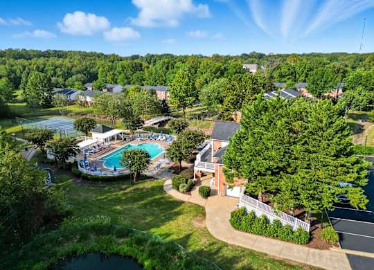 A bird's eye view of a residential area with a swimming pool and tennis court.