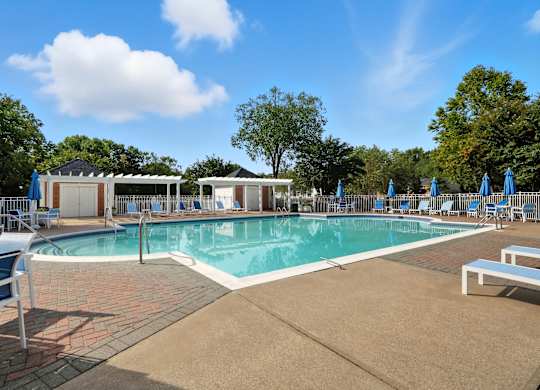 A large outdoor swimming pool surrounded by blue lounge chairs and umbrellas.