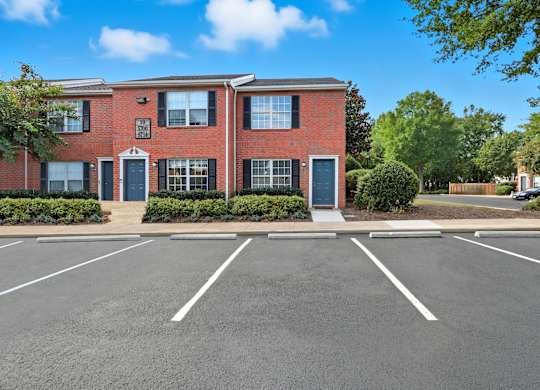A red brick building with a parking lot in front.