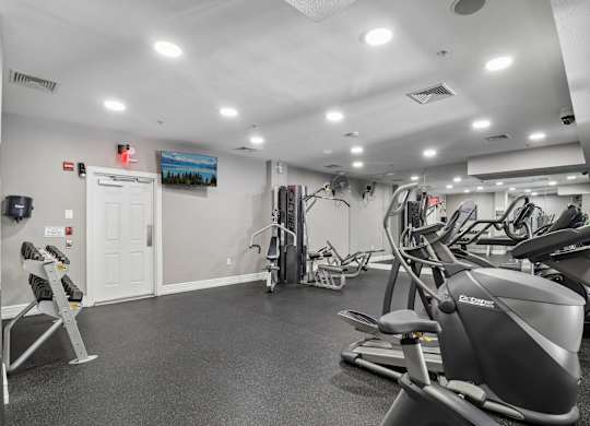 A gym with a variety of exercise equipment including treadmills, stationary bikes, and weight machines.